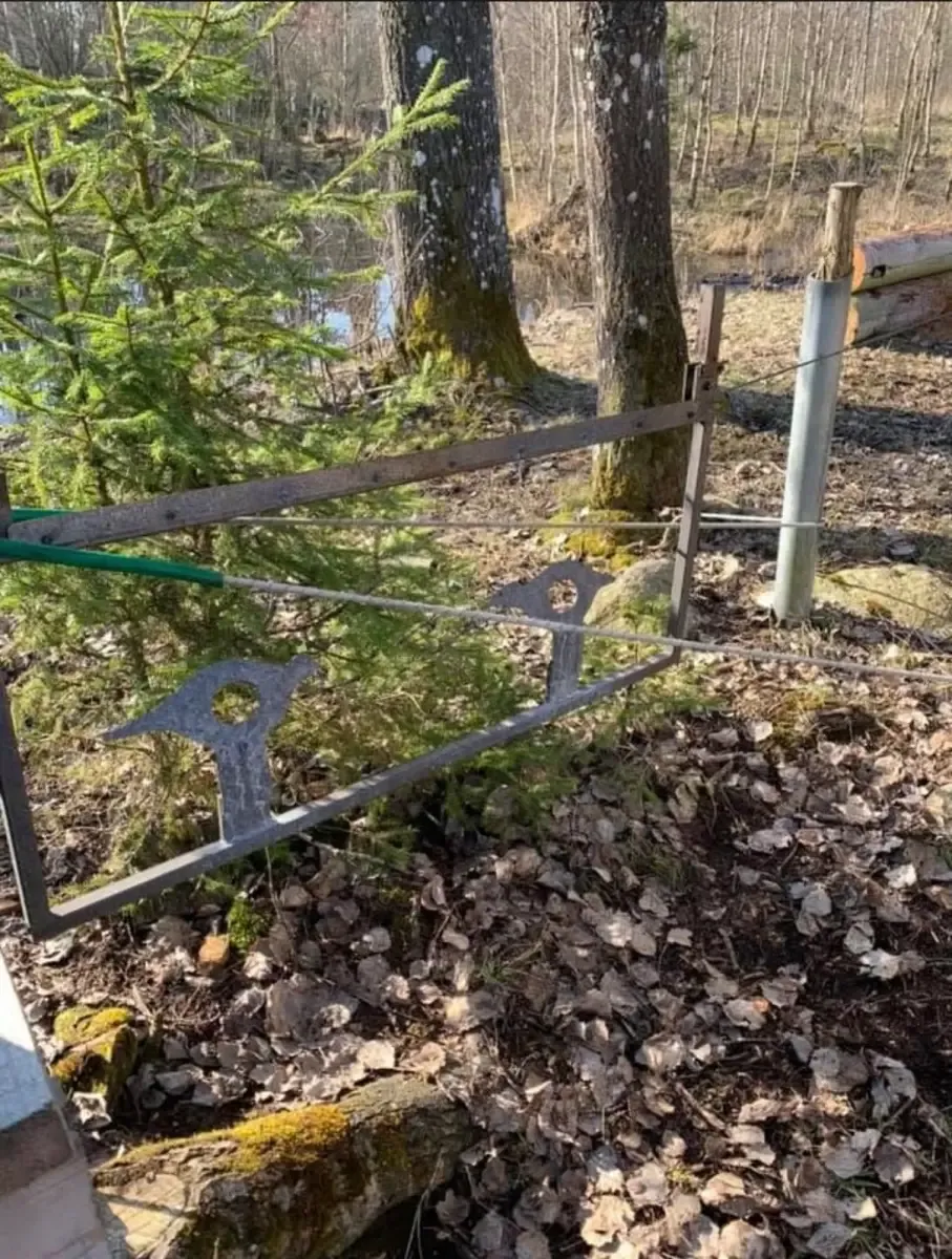 Utskuren plåtfigur med träffhål, upphängd i en lina mellan stolpar